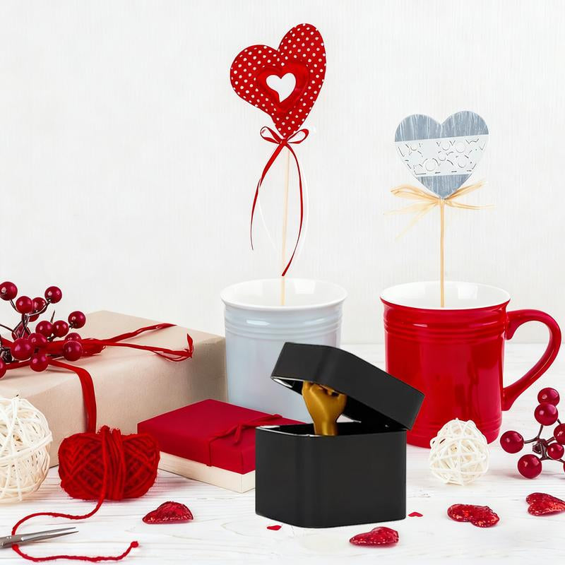 Valentine's Day gifts with red and white mugs, heart decorations, wrapped presents, and a black ring box